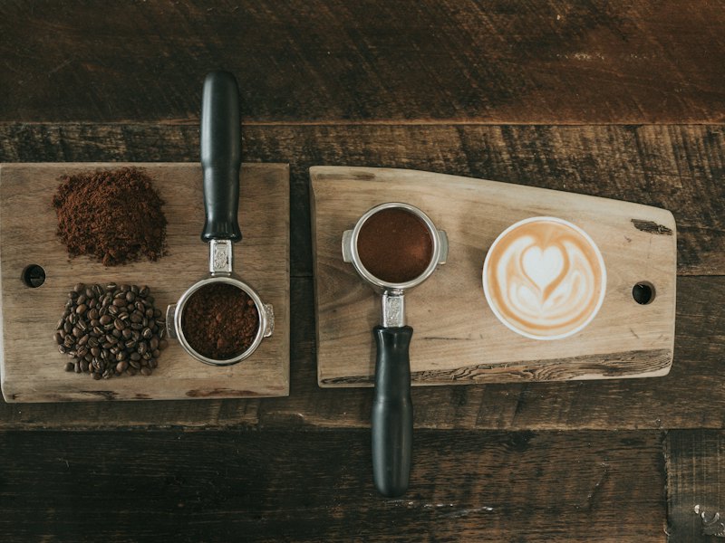 Coffee beans beside coffee powder on brown wooden board