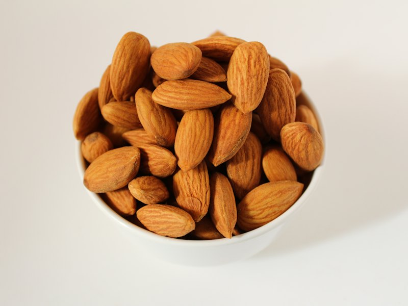 Brown almond nuts on white ceramic bowl